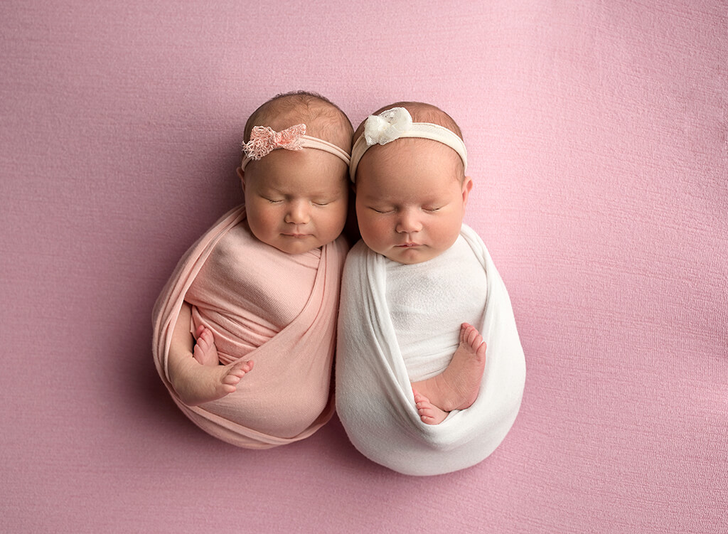 Beautiful infant Photography: baby girl twins posing on a pink blanket at a newborn photography studio in Hobe Sound Florida