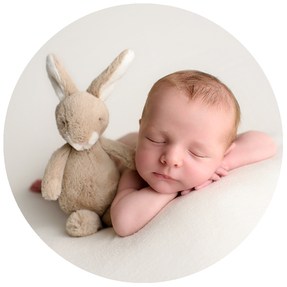 Handsome infant boy posing with his baby bunny during his newborn Photography studio session in Palm Beach County Florida