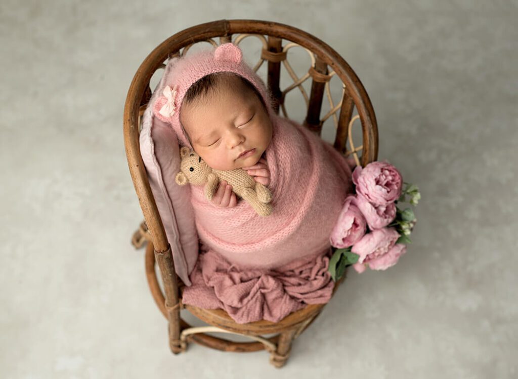 Newborn girl surrounded by whimsical props in a photography session